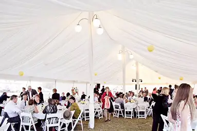 Inside view of a sophisticated white marquee for a private party hire in Moree, with elegant white chairs, guests dining and yellow decorative accents.