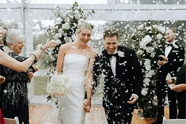 Bride and groom in joyful celebration, walking down the aisle amidst a petal toss, beautifully arranged by a private party hire service in Moree.